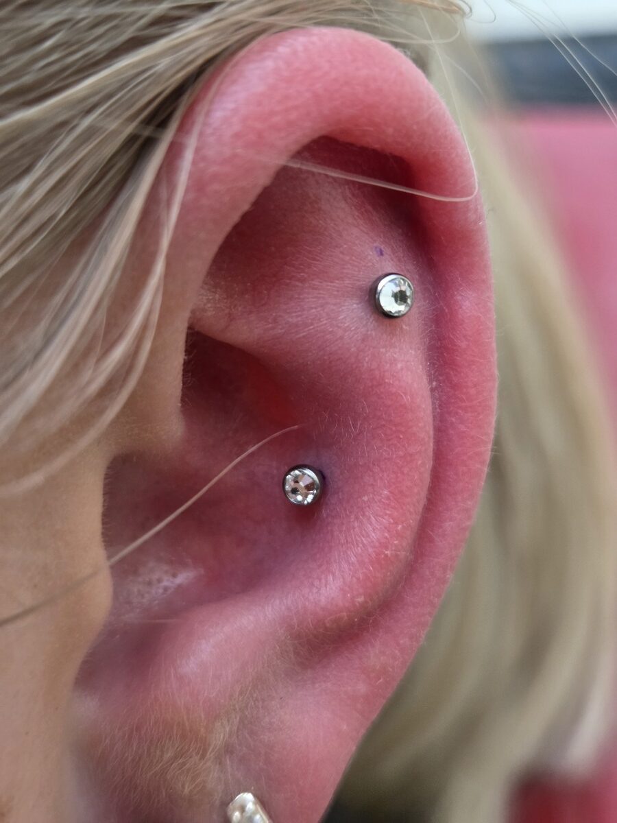 Nahaufnahme eines Ohrs mit neutralem Ausdruck und zwei silbernen Piercings